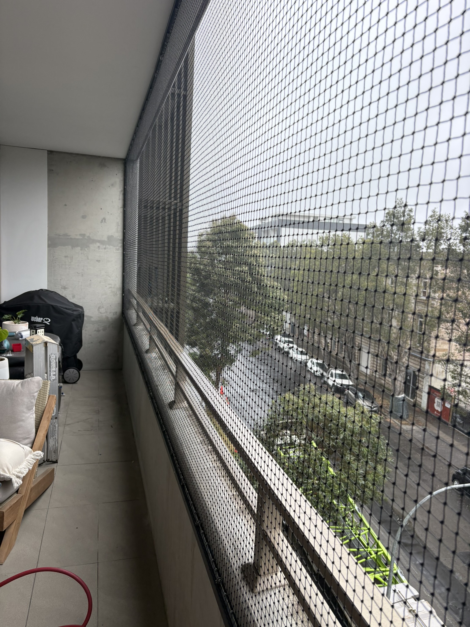 Floor-to-ceiling black cat netting enclosing an apartment balcony